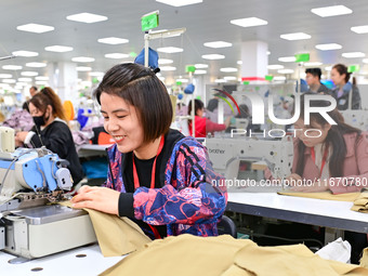 Workers rush to fulfill export orders at the clothing production line of Shaanxi Yanzhong Garment Co., Ltd. in Weinan, China, on October 15,...