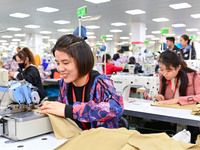 Workers rush to fulfill export orders at the clothing production line of Shaanxi Yanzhong Garment Co., Ltd. in Weinan, China, on October 15,...