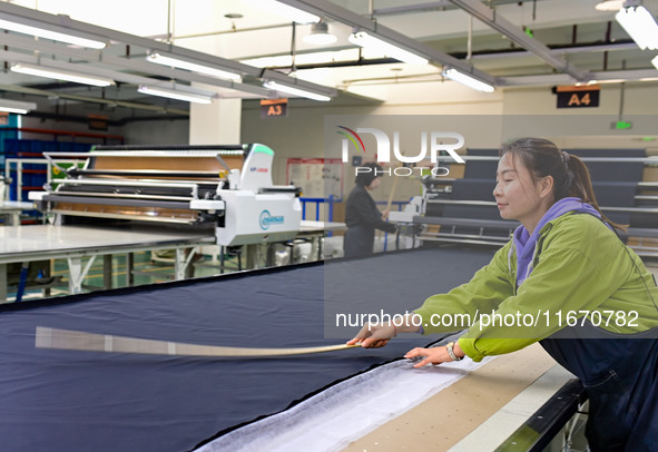 Workers rush to fulfill export orders at the clothing production line of Shaanxi Yanzhong Garment Co., Ltd. in Weinan, China, on October 15,...