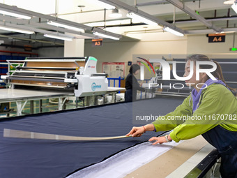 Workers rush to fulfill export orders at the clothing production line of Shaanxi Yanzhong Garment Co., Ltd. in Weinan, China, on October 15,...