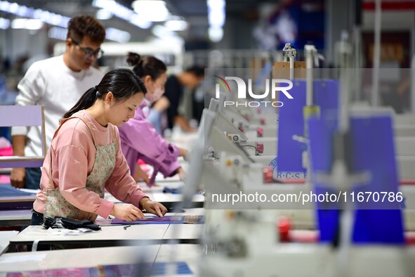 Workers rush to fulfill export orders at the clothing production line of Shaanxi Yanzhong Garment Co., Ltd. in Weinan, China, on October 15,...