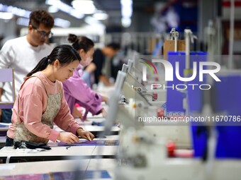 Workers rush to fulfill export orders at the clothing production line of Shaanxi Yanzhong Garment Co., Ltd. in Weinan, China, on October 15,...