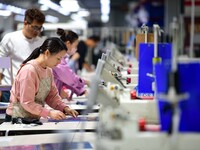 Workers rush to fulfill export orders at the clothing production line of Shaanxi Yanzhong Garment Co., Ltd. in Weinan, China, on October 15,...