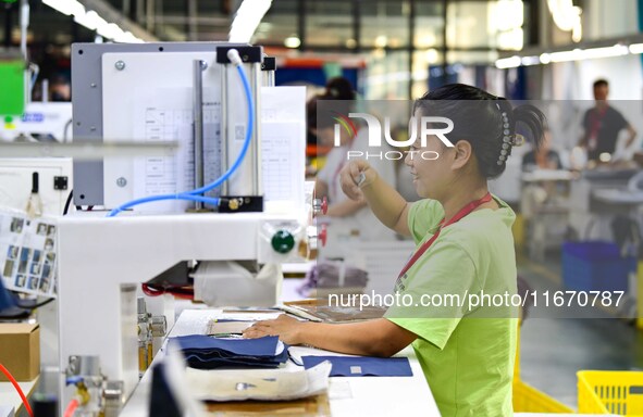 Workers rush to fulfill export orders at the clothing production line of Shaanxi Yanzhong Garment Co., Ltd. in Weinan, China, on October 15,...