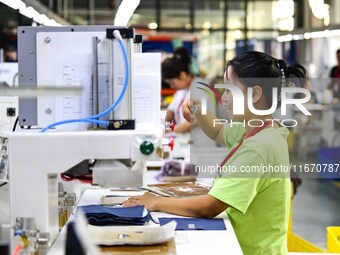 Workers rush to fulfill export orders at the clothing production line of Shaanxi Yanzhong Garment Co., Ltd. in Weinan, China, on October 15,...