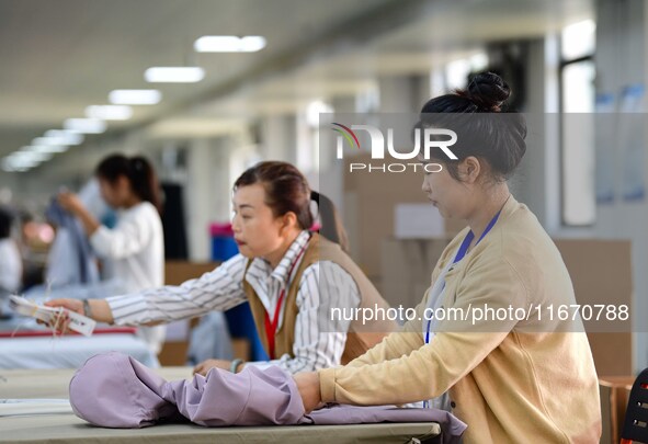 Workers rush to fulfill export orders at the clothing production line of Shaanxi Yanzhong Garment Co., Ltd. in Weinan, China, on October 15,...