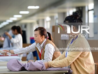 Workers rush to fulfill export orders at the clothing production line of Shaanxi Yanzhong Garment Co., Ltd. in Weinan, China, on October 15,...