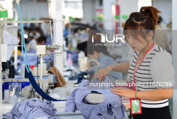 Workers rush to fulfill export orders at the clothing production line of Shaanxi Yanzhong Garment Co., Ltd. in Weinan, China, on October 15,...