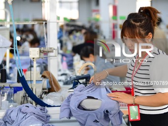 Workers rush to fulfill export orders at the clothing production line of Shaanxi Yanzhong Garment Co., Ltd. in Weinan, China, on October 15,...