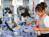 Workers rush to fulfill export orders at the clothing production line of Shaanxi Yanzhong Garment Co., Ltd. in Weinan, China, on October 15,...