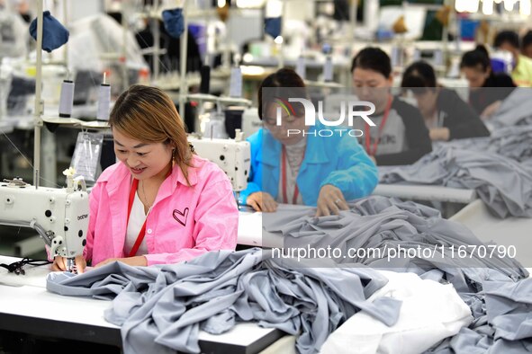 Workers rush to fulfill export orders at the clothing production line of Shaanxi Yanzhong Garment Co., Ltd. in Weinan, China, on October 15,...