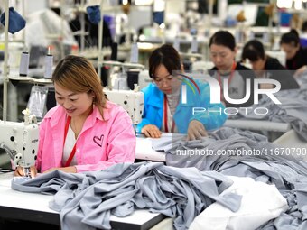 Workers rush to fulfill export orders at the clothing production line of Shaanxi Yanzhong Garment Co., Ltd. in Weinan, China, on October 15,...