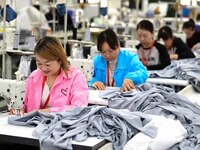 Workers rush to fulfill export orders at the clothing production line of Shaanxi Yanzhong Garment Co., Ltd. in Weinan, China, on October 15,...