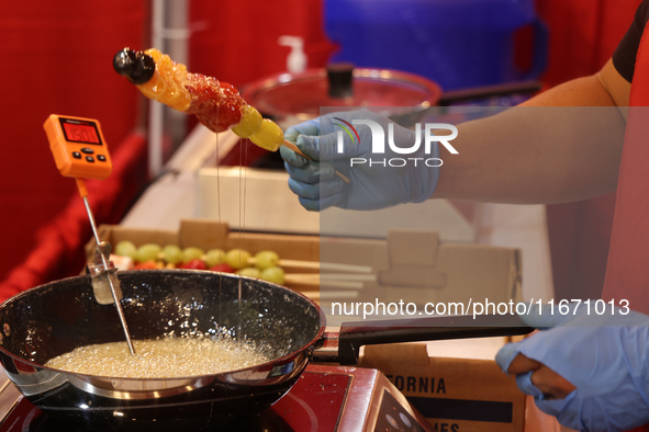 A man coats fruit skewers in molten sugar while preparing Tanghulu (candied fruit skewers) in Markham, Ontario, Canada, on October 5, 2024....