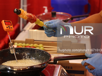 A man coats fruit skewers in molten sugar while preparing Tanghulu (candied fruit skewers) in Markham, Ontario, Canada, on October 5, 2024....