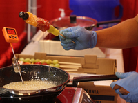 A man coats fruit skewers in molten sugar while preparing Tanghulu (candied fruit skewers) in Markham, Ontario, Canada, on October 5, 2024....