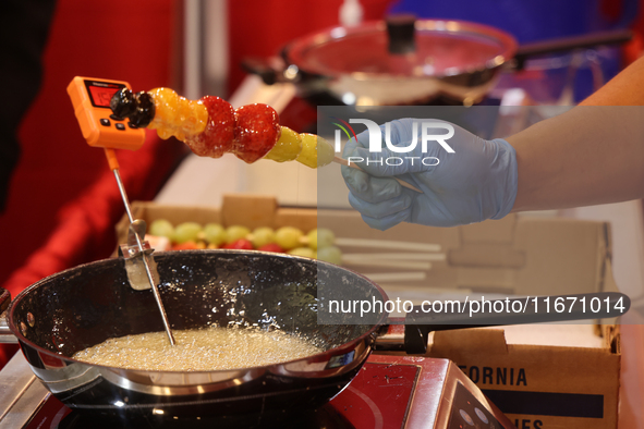 A man coats fruit skewers in molten sugar while preparing Tanghulu (candied fruit skewers) in Markham, Ontario, Canada, on October 5, 2024....