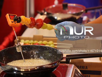 A man coats fruit skewers in molten sugar while preparing Tanghulu (candied fruit skewers) in Markham, Ontario, Canada, on October 5, 2024....