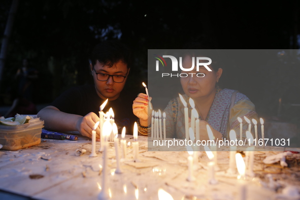 Devotees light candles during the celebrations to mark the Buddhist festival of Probarona Purnima in Dhaka, Bangladesh, on October 16, 2024....