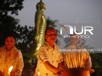 Devotees light candles during the celebrations to mark the Buddhist festival of Probarona Purnima in Dhaka, Bangladesh, on October 16, 2024....