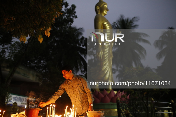 A devotee lights a candle during the celebrations to mark the Buddhist festival of Probarona Purnima in Dhaka, Bangladesh, on October 16, 20...