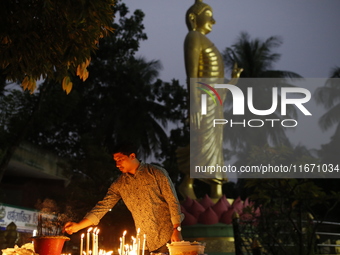 A devotee lights a candle during the celebrations to mark the Buddhist festival of Probarona Purnima in Dhaka, Bangladesh, on October 16, 20...