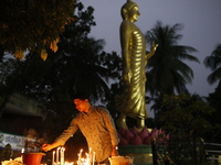 A devotee lights a candle during the celebrations to mark the Buddhist festival of Probarona Purnima in Dhaka, Bangladesh, on October 16, 20...