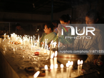 Devotees light candles during the celebrations to mark the Buddhist festival of Probarona Purnima in Dhaka, Bangladesh, on October 16, 2024....