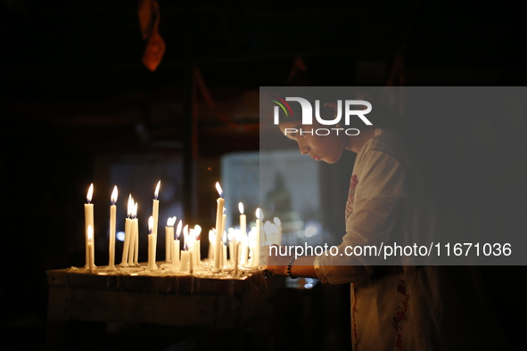 A devotee lights a candle during the celebrations to mark the Buddhist festival of Probarona Purnima in Dhaka, Bangladesh, on October 16, 20...