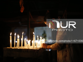 A devotee lights a candle during the celebrations to mark the Buddhist festival of Probarona Purnima in Dhaka, Bangladesh, on October 16, 20...