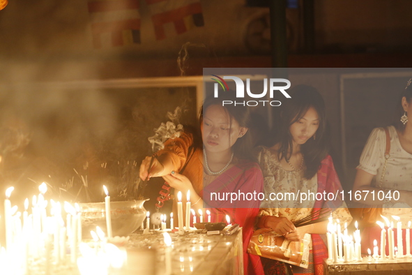 Devotees light candles during the celebrations to mark the Buddhist festival of Probarona Purnima in Dhaka, Bangladesh, on October 16, 2024....