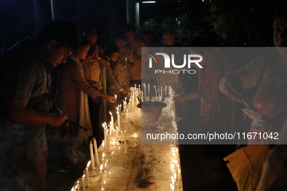 Devotees light candles during the celebrations to mark the Buddhist festival of Probarona Purnima in Dhaka, Bangladesh, on October 16, 2024....