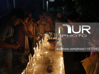 Devotees light candles during the celebrations to mark the Buddhist festival of Probarona Purnima in Dhaka, Bangladesh, on October 16, 2024....