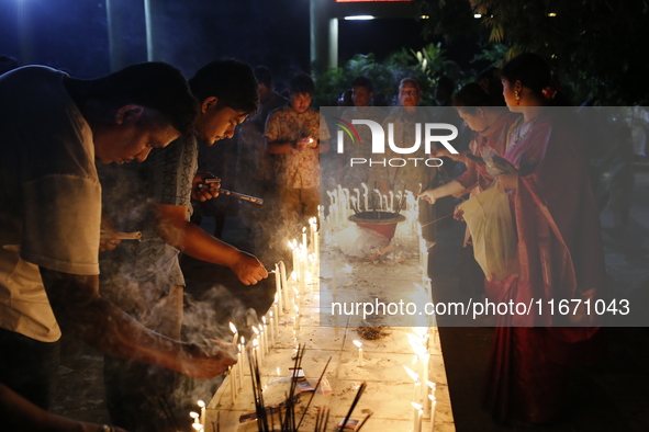 Devotees light candles during the celebrations to mark the Buddhist festival of Probarona Purnima in Dhaka, Bangladesh, on October 16, 2024....