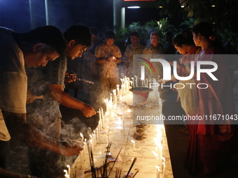 Devotees light candles during the celebrations to mark the Buddhist festival of Probarona Purnima in Dhaka, Bangladesh, on October 16, 2024....