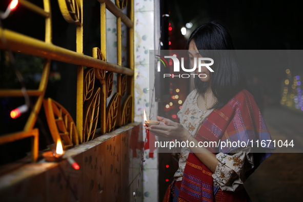 A devotee lights an oil lamp during the celebrations to mark the Buddhist festival of Probarona Purnima in Dhaka, Bangladesh, on October 16,...