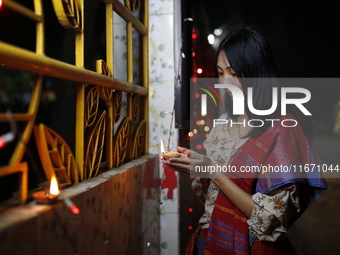 A devotee lights an oil lamp during the celebrations to mark the Buddhist festival of Probarona Purnima in Dhaka, Bangladesh, on October 16,...