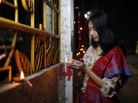 A devotee lights an oil lamp during the celebrations to mark the Buddhist festival of Probarona Purnima in Dhaka, Bangladesh, on October 16,...