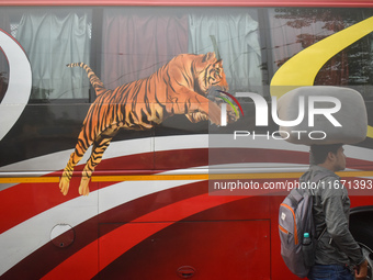 A person carries a sack on his head while walking next to a bus inside a bus stand in Kolkata, India, on October 16, 2024. (