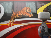 A person carries a sack on his head while walking next to a bus inside a bus stand in Kolkata, India, on October 16, 2024. (