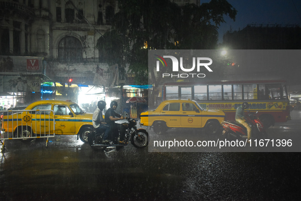 People stand at a traffic signal during heavy rain in Kolkata, India, on October 16, 2024. 