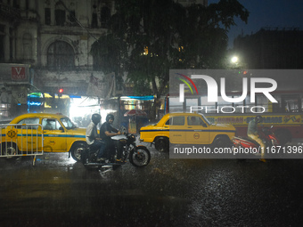 People stand at a traffic signal during heavy rain in Kolkata, India, on October 16, 2024. (