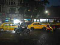 People stand at a traffic signal during heavy rain in Kolkata, India, on October 16, 2024. (