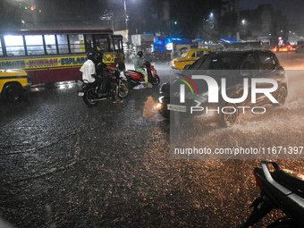 People stand at a traffic signal during heavy rain in Kolkata, India, on October 16, 2024. (