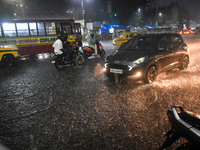 People stand at a traffic signal during heavy rain in Kolkata, India, on October 16, 2024. (