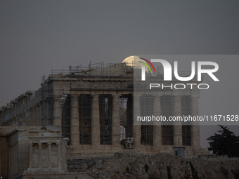 The 'Hunter's supermoon' rises above the Greek Parthenon Temple (438 BC), covered by scaffolding, at the Acropolis archaeological site in At...