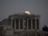 The 'Hunter's supermoon' rises above the Greek Parthenon Temple (438 BC), covered by scaffolding, at the Acropolis archaeological site in At...