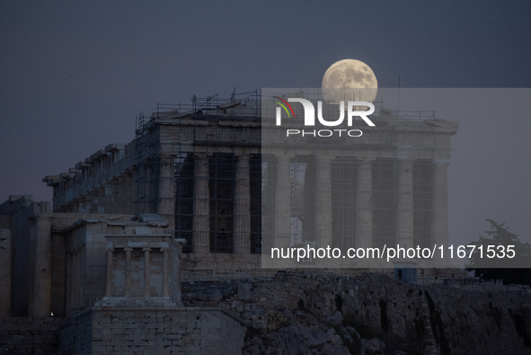 The 'Hunter's supermoon' rises above the Greek Parthenon Temple (438 BC), covered by scaffolding, at the Acropolis archaeological site in At...