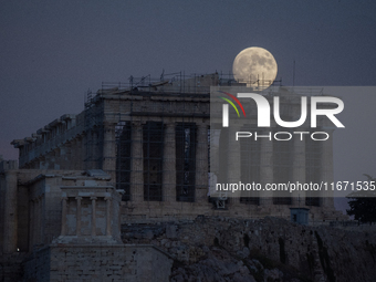 The 'Hunter's supermoon' rises above the Greek Parthenon Temple (438 BC), covered by scaffolding, at the Acropolis archaeological site in At...