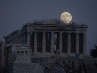 The 'Hunter's supermoon' rises above the Greek Parthenon Temple (438 BC), covered by scaffolding, at the Acropolis archaeological site in At...